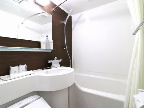 a bathroom with a sink and a bath tub at Central Hotel Okayama in Okayama