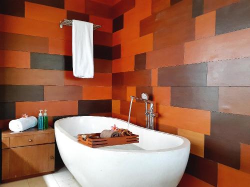 a bathroom with a white tub and a colorful wall at The Batu Hotel & Villas in Batu