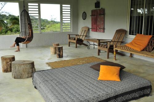 a bedroom with a bed and chairs and a person doing a swing at Létan Lontan in Rodrigues Island
