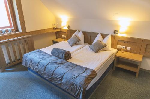 a bedroom with a large bed with a blue blanket at Hotel Krvavec in Cerklje na Gorenjskem