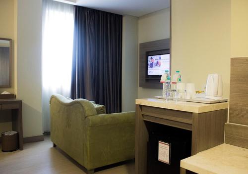 a living room with a green couch and a television at BW Kemayoran Hotel & Convention Powered by Archipelago in Jakarta