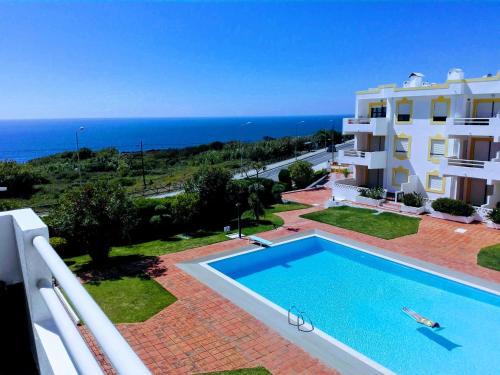 a view of a building with a swimming pool and the ocean at Ericeira Sunset Lifestyle II in Ericeira