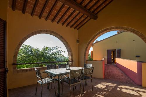 d'une terrasse avec une table, des chaises et deux arches. dans l'établissement Tenuta Moriano, à Montespertoli