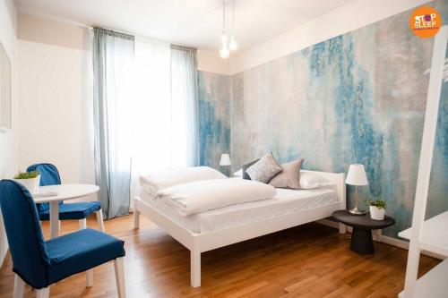a bedroom with a white bed and a blue accent wall at Stop & Sleep Venzone in Venzone