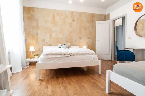 a bedroom with a white bed and a wooden floor at Stop & Sleep Venzone in Venzone