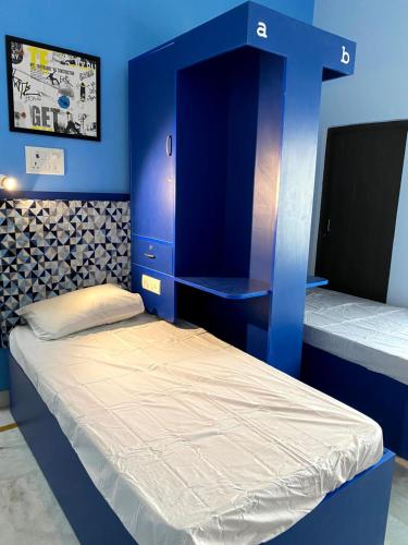 a blue room with two beds and a tv at Backpackers Den in Lucknow