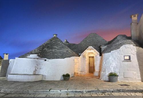 a white building with a black roof with a door at Trulli Holiday Deluxe & Wellness in Alberobello