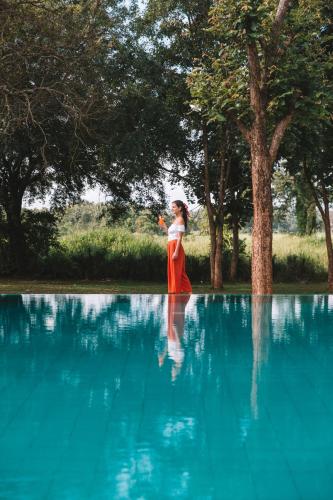 a woman in a red dress standing next to a pool of water at Sevanagama in Habarana