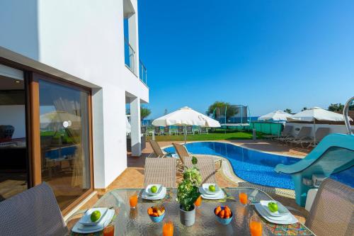 a patio with a table and a swimming pool at Seafront Protaras Villas in Protaras