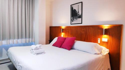 1 dormitorio con 1 cama blanca grande con almohadas rojas en Hostal Doña Isabel en Majadahonda