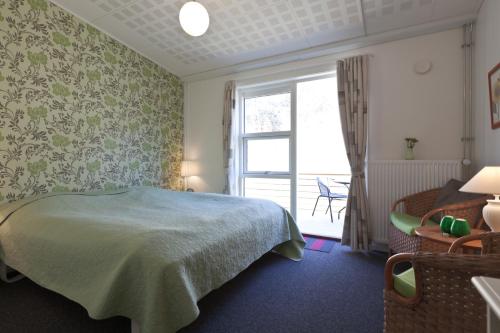 ein Schlafzimmer mit einem Bett, einem Fenster und einem Stuhl in der Unterkunft Bromølle Kro in Jyderup