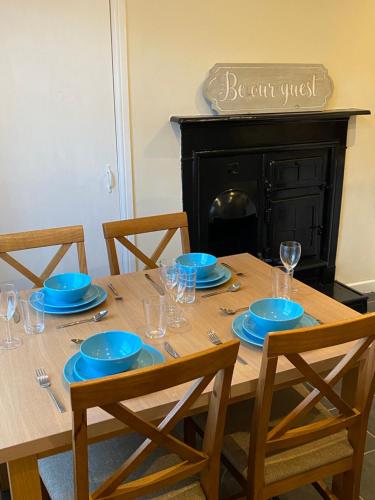 una mesa de madera con placas azules y vasos. en Ashington Home from Home en Ashington
