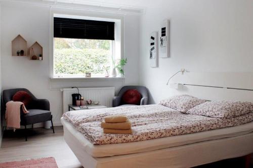 1 Schlafzimmer mit einem Bett mit 2 Stühlen und einem Fenster in der Unterkunft Nordkap Bed & Bath in Holstebro
