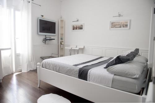 a white bedroom with a bed and a flat screen tv at Casa San Vito in Monopoli