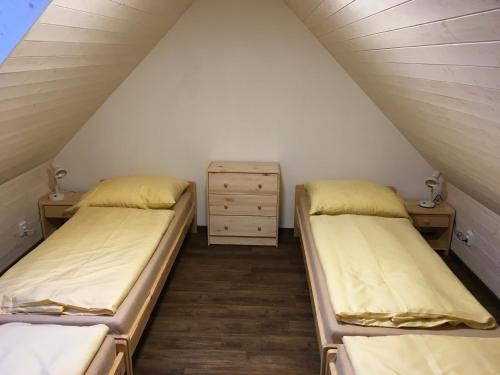 2 Betten in einem Dachzimmer mit einer Kommode in der Unterkunft Apartman Herman in Rudník