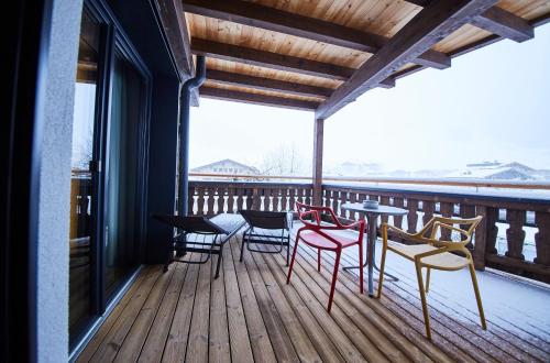 a porch with chairs and tables on a deck at THOMSN Central Hotel & Appartements in Saalbach Hinterglemm