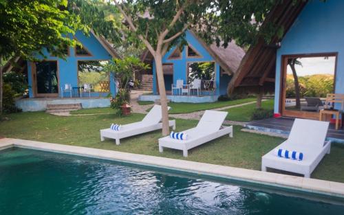 une piscine avec deux chaises longues et une maison dans l'établissement Blue Monkey Retreat Areguling Lombok, à Kuta Lombok