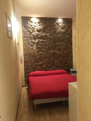een rood bed in een kamer met een stenen muur bij B&B In Piazza in Rome