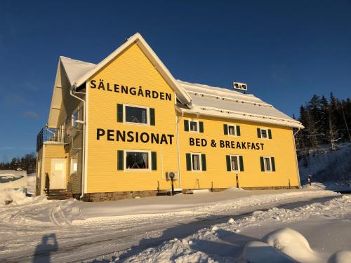 uma casa amarela com um sinal na neve em Sälengården em Vörderås