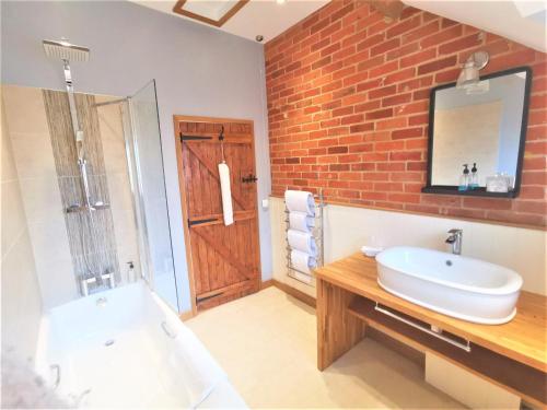 baño con lavabo blanco y pared de ladrillo en Blashford Manor Farmhouse - New Forest Cottage en Ringwood