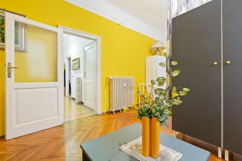 een gele kamer met een vaas op een tafel bij Loreto Courtyard Apartment in Milaan