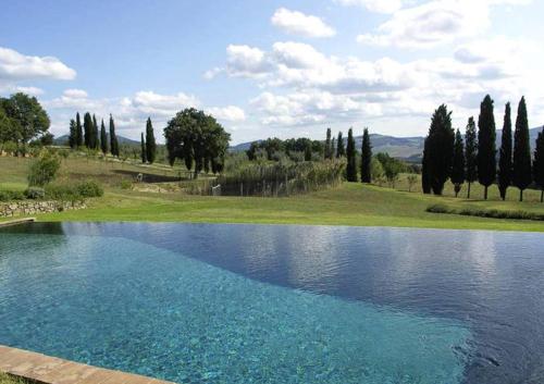 uma grande piscina de água azul com árvores ao fundo em Villa Vallocchie em Sarteano