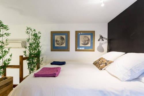 セビリアにあるPRETTY DUPLEX IN BOHEMIAN DISTRICT-CITY CENTERの白いベッド1台、壁に2枚の写真が飾られたベッドルーム1室