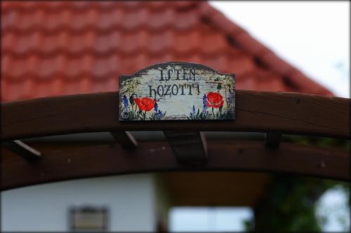 a sign on a fence with poppies on it at Kaláris Vendégház in Hollókő