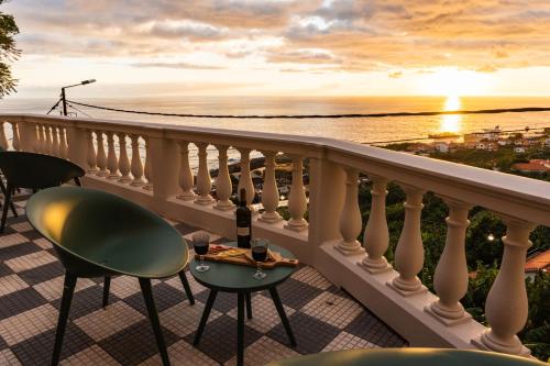 a balcony with a table and chairs and a view of the ocean at 1905 Zino's Palace in Ponta do Sol