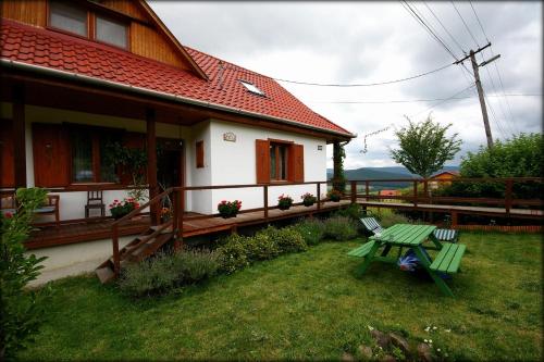 una casa con una mesa de picnic verde en el patio en Kaláris Vendégház, en Hollókő