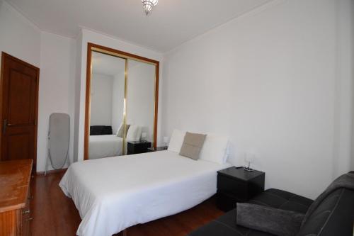 a bedroom with a white bed and a couch at Wonderful view in the city center in Faro