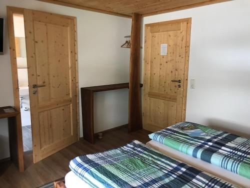 two beds in a room with wooden doors at Pension Hofeck in Bernau im Schwarzwald