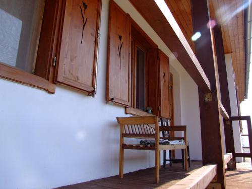 una silla de madera sentada en el lateral de una casa en Kaláris Vendégház en Hollókő