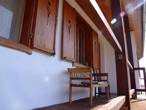 a wooden chair sitting on the side of a house at Kaláris Vendégház in Hollókő