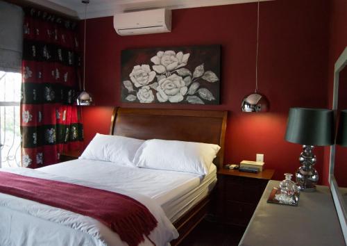 a bedroom with a bed with a red wall at Casa de Ross in Pretoria