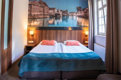 a bedroom with a large bed with a painting on the wall at Apart Neptun in Gdańsk