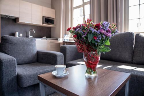 a vase of flowers on a table with a cup of coffee at Apart Neptun in Gdańsk