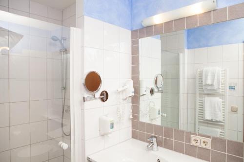 a bathroom with a shower and a sink and a mirror at Hotel Seltenbacher Hof in Tuttlingen