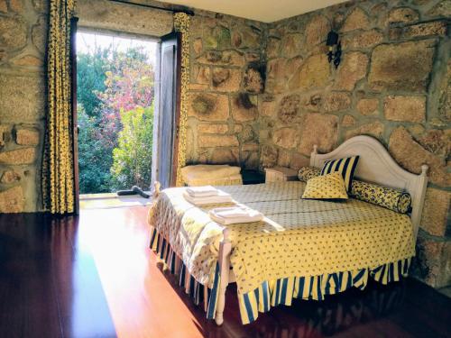 1 dormitorio con 1 cama en una pared de piedra en Casa da Costeira, en Figueiró