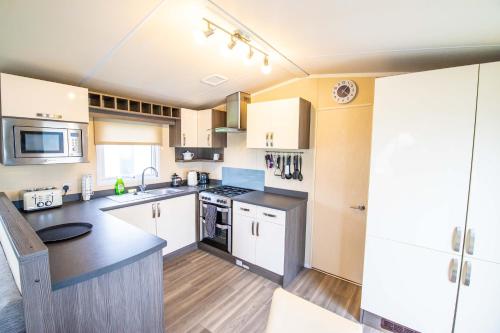 a kitchen with white cabinets and a counter top at Big Skies Platinum Plus Holiday Home with Wifi, Netflix, Dishwasher, Decking in Camber