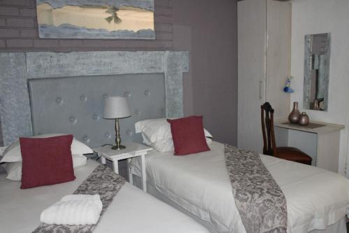 a hotel room with two beds with red pillows at Ukarimu Guest House in Klerksdorp