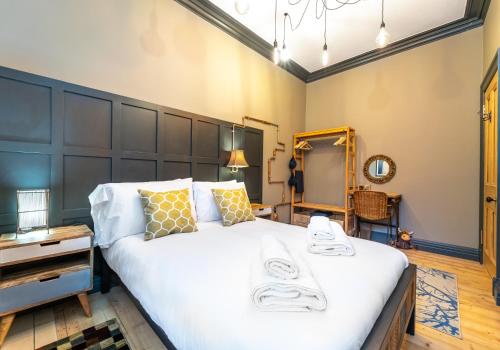 een slaapkamer met een groot wit bed en een spiegel bij The Waverley Park Residence in Edinburgh