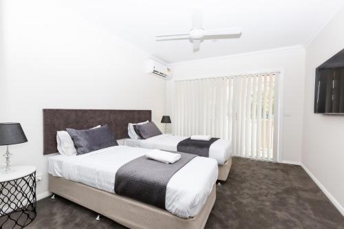 2 bedden in een slaapkamer met witte muren en een raam bij Wagga Apartments #1 in Wagga Wagga