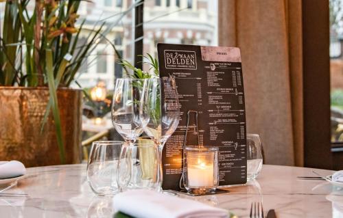 a table with wine glasses and a menu on it at De Zwaan Delden in Delden