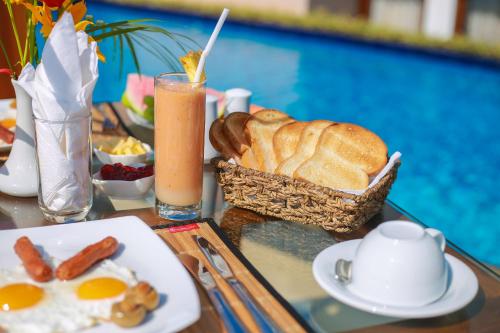 a table with a breakfast of bread and eggs and a drink at Mount Marina Villas 12 in Galle