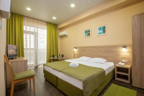 ein Hotelzimmer mit einem Bett und einem TV in der Unterkunft Hotel Pelican in Krasnodar