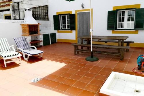 a patio with a bench and a table and chairs at Casa Mareco in Vila Nova de Milfontes