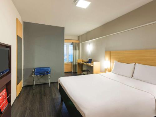 a hotel room with a large bed and a blue chair at ibis Fortaleza Praia de Iracema in Fortaleza