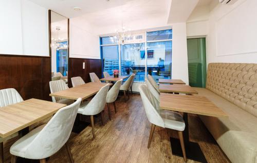 a restaurant with wooden tables and white chairs at Boutique Hotel Nea in Brčko