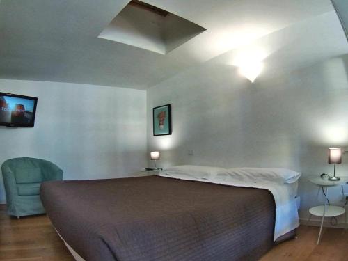 a bedroom with a large bed and a blue chair at La Maison del Capestrano in Milan